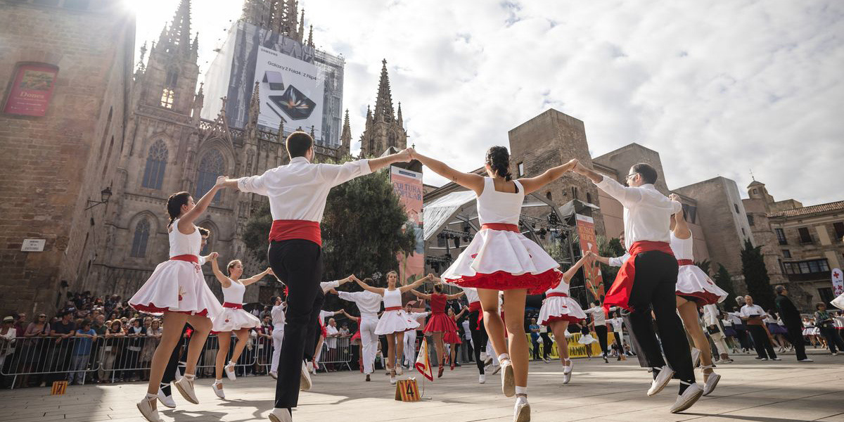 Un gruppo di ballerini in abiti bianchi e rossi si esibisce in una piazza cittadina.