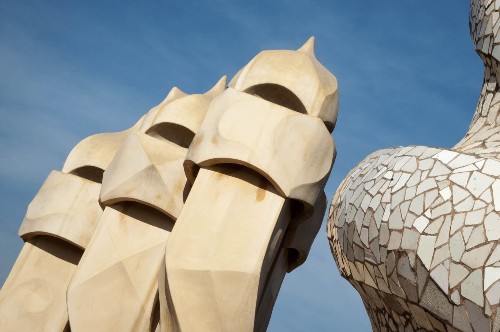 Si vede un dettaglio scultoreo della facciata della Pedrera contro il cielo azzurro.