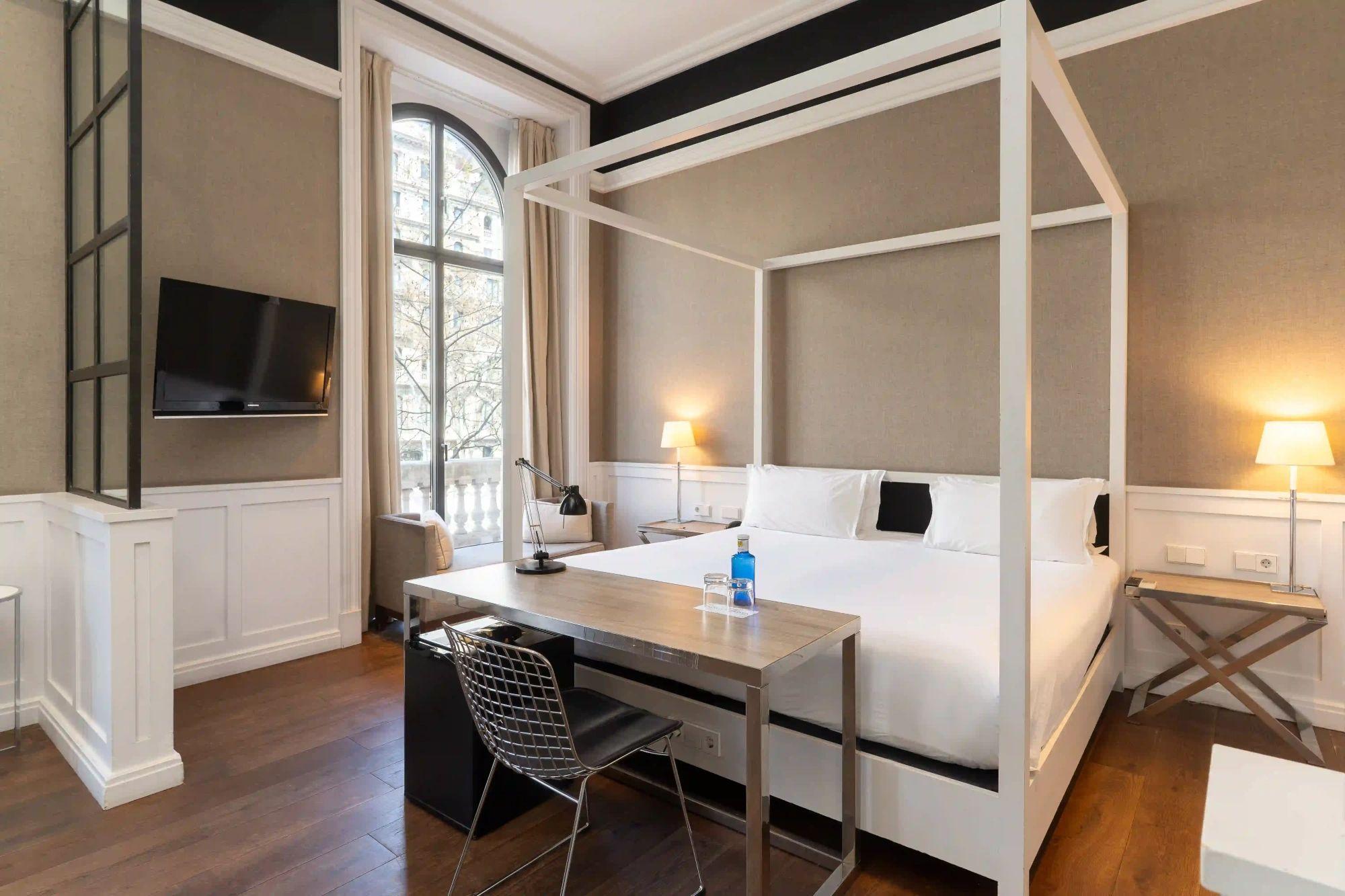 Se ve una habitación con cama, escritorio, sofá y una ventana con luz natural.
