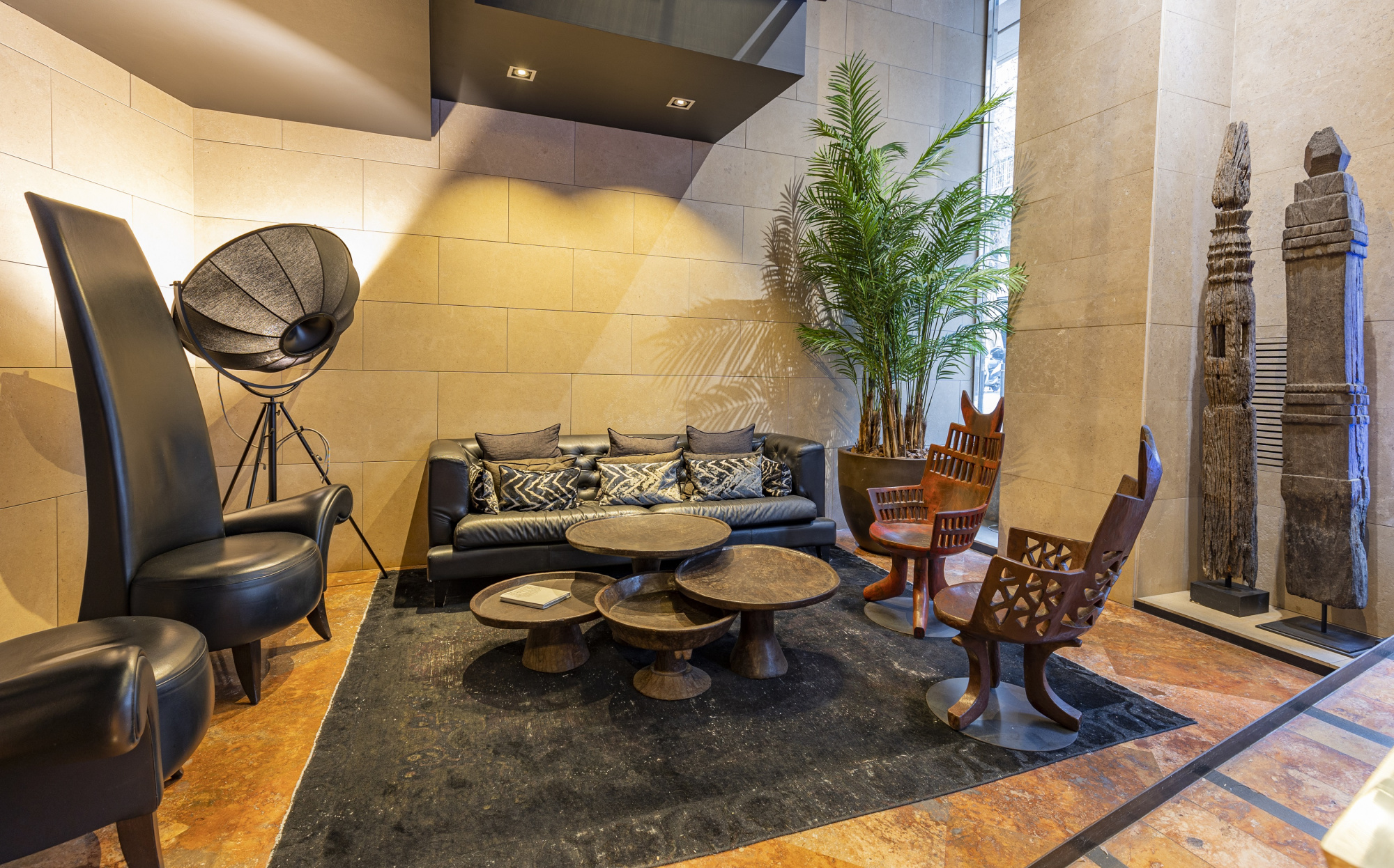 Se ve una zona de estar con sillones, mesas bajas y decoración con plantas y esculturas en el interior.