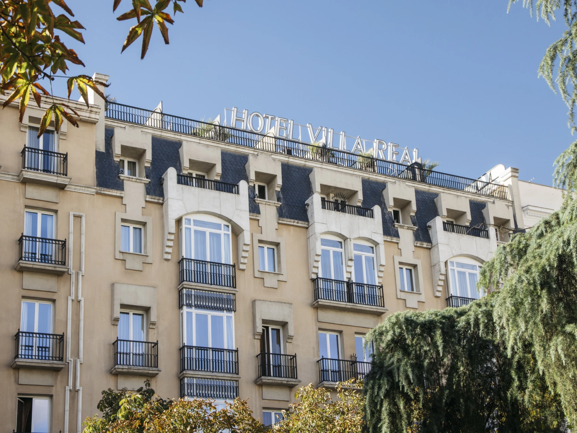 Se ve la fachada del edificio con balcones y ventanas, bajo un cielo despejado.