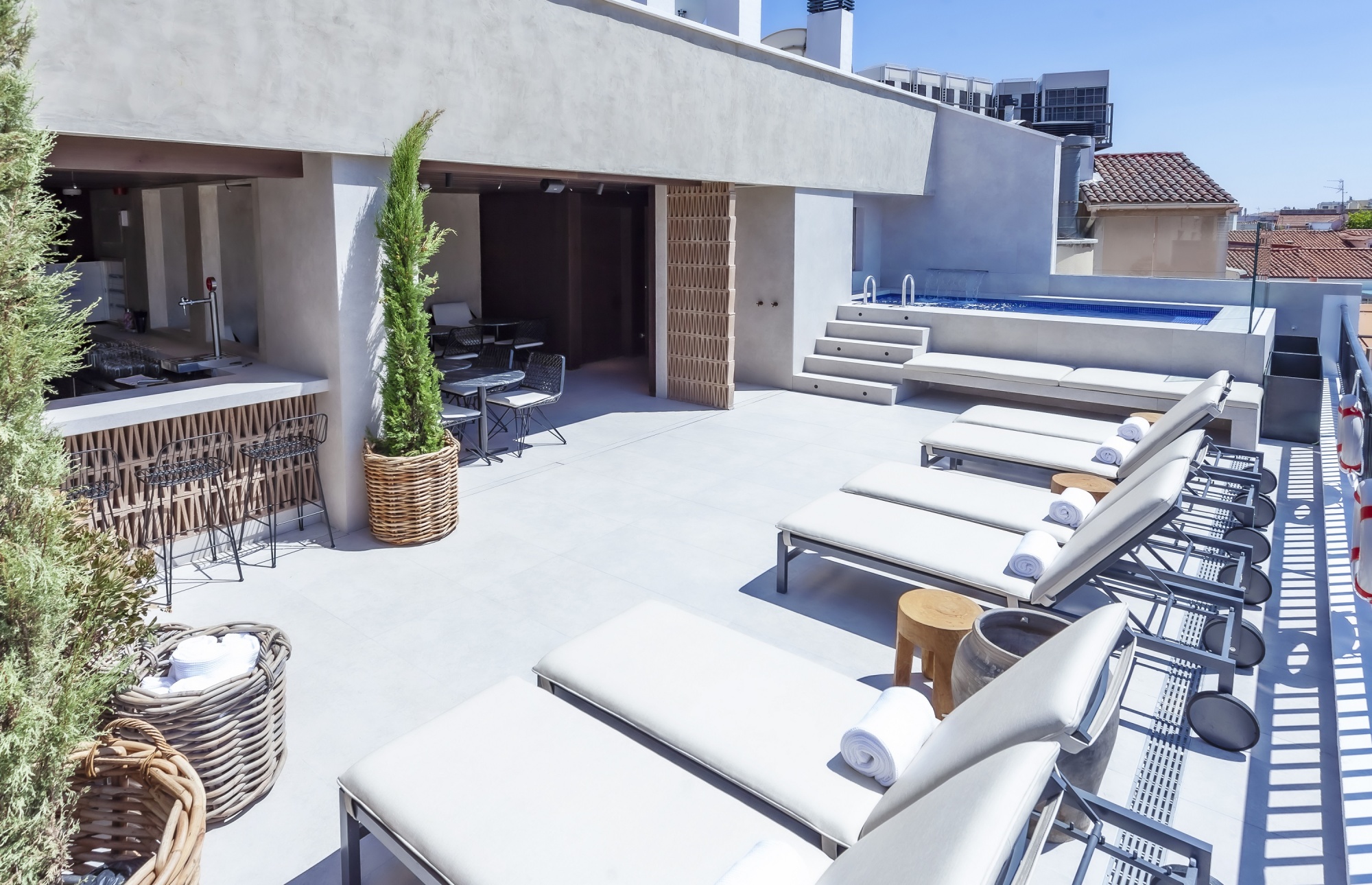 Terraza en la azotea con tumbonas, mesas y una zona de descanso al aire libre.
