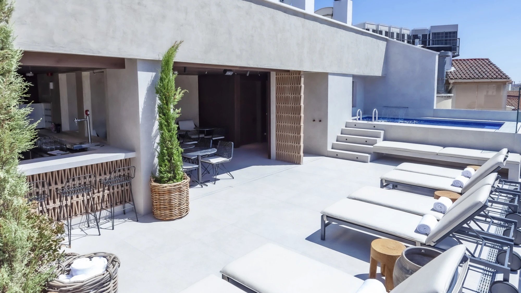 Terraza en la azotea con tumbonas, zona de descanso y piscina al fondo.