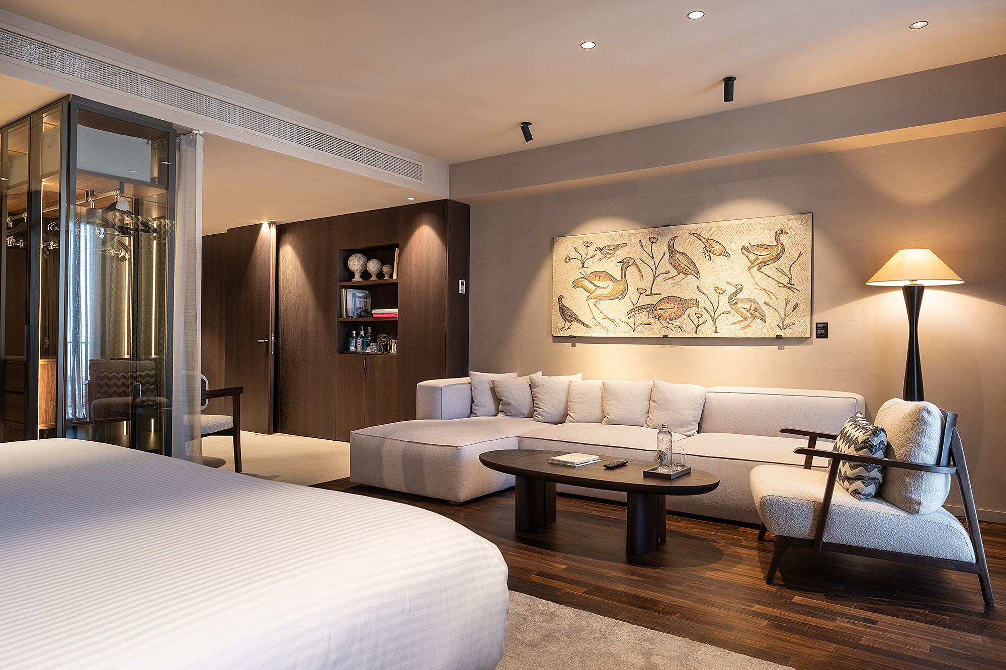Suite premium con cama doble, sofá y mesa de centro en una sala luminosa.