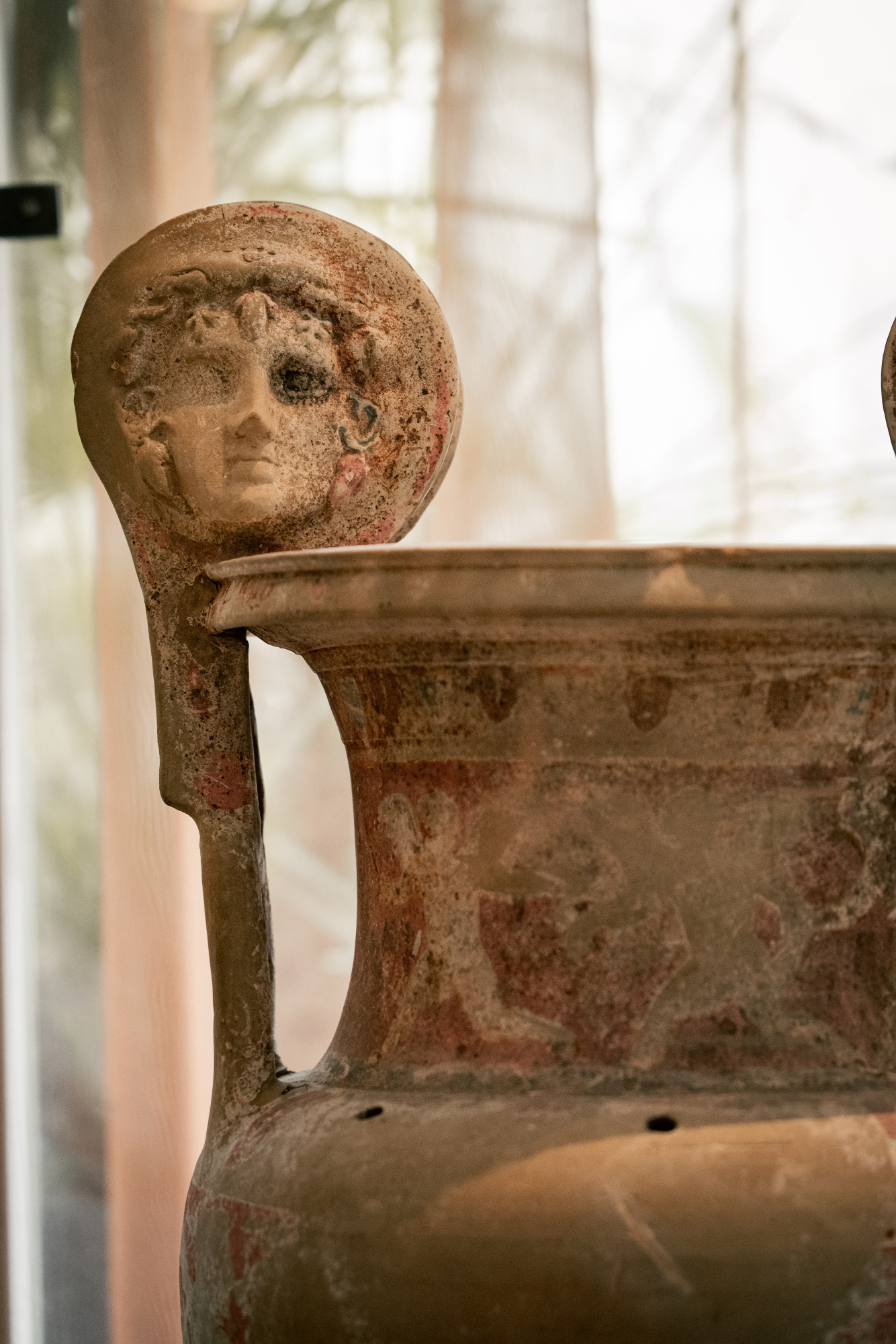 Se ve una escultura decorativa de cerámica con forma de figura humana junto a una pieza de cerámica en primer plano.