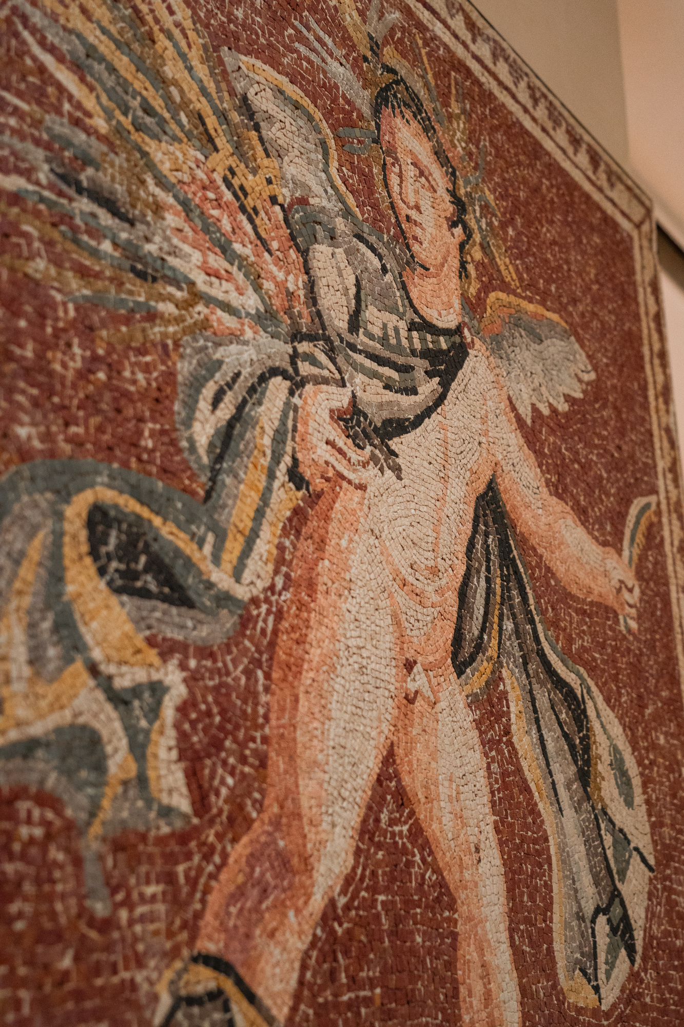 Se ve un mosaico romano decorativo con una figura humana sobre un fondo de colores.