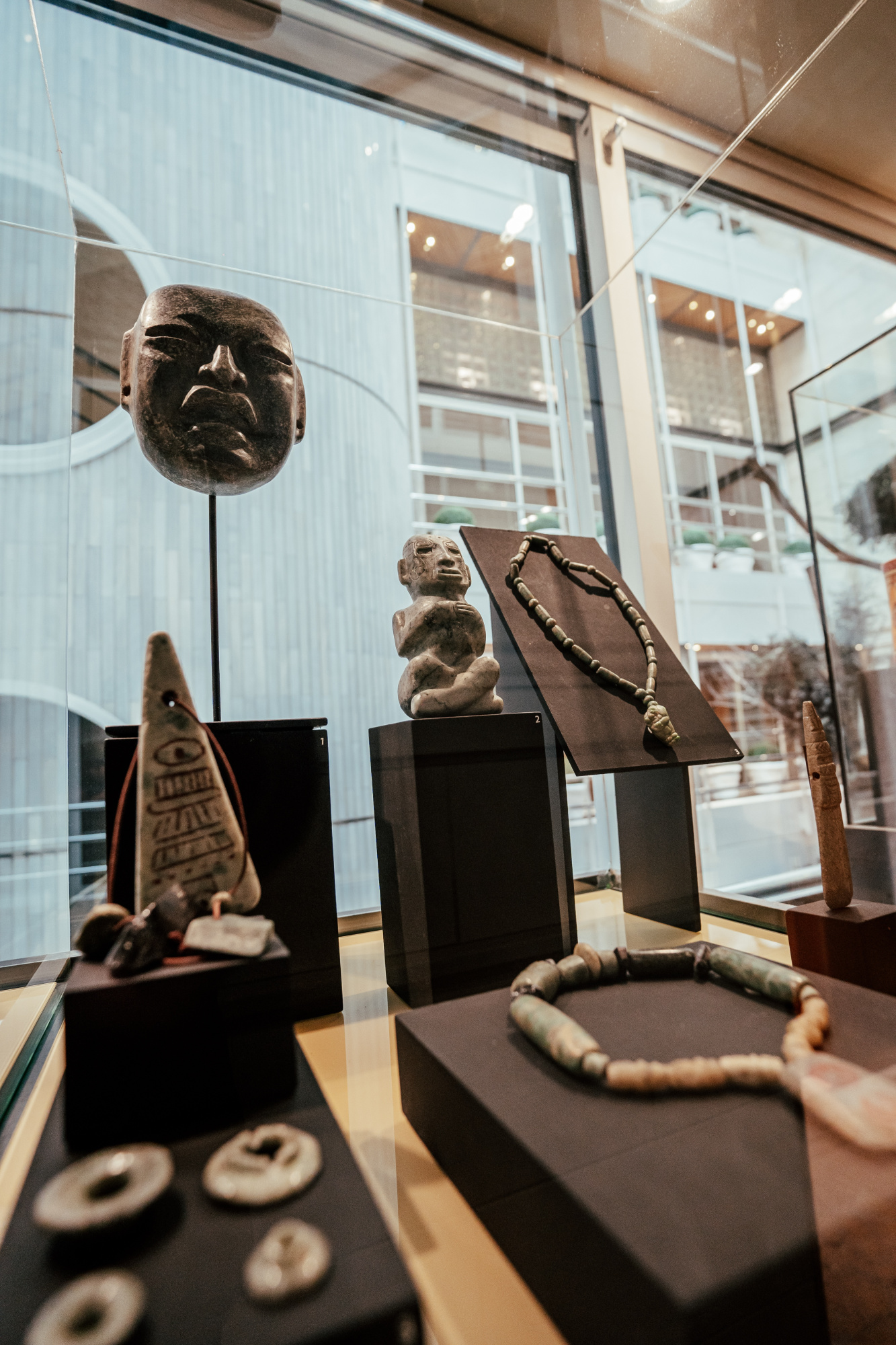 Se ve una vitrina con figuras y objetos arqueológicos sobre pedestales en una sala interior.