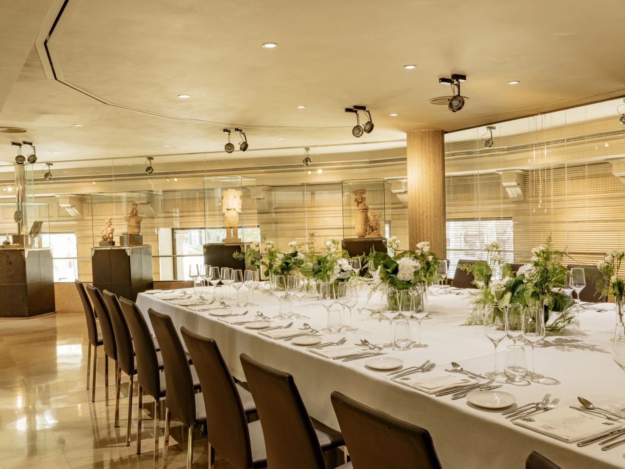 Una elegante mesa de banquete decorada con vajilla fina y centros de mesa florales, ideal para eventos culturales en un entorno sofisticado.