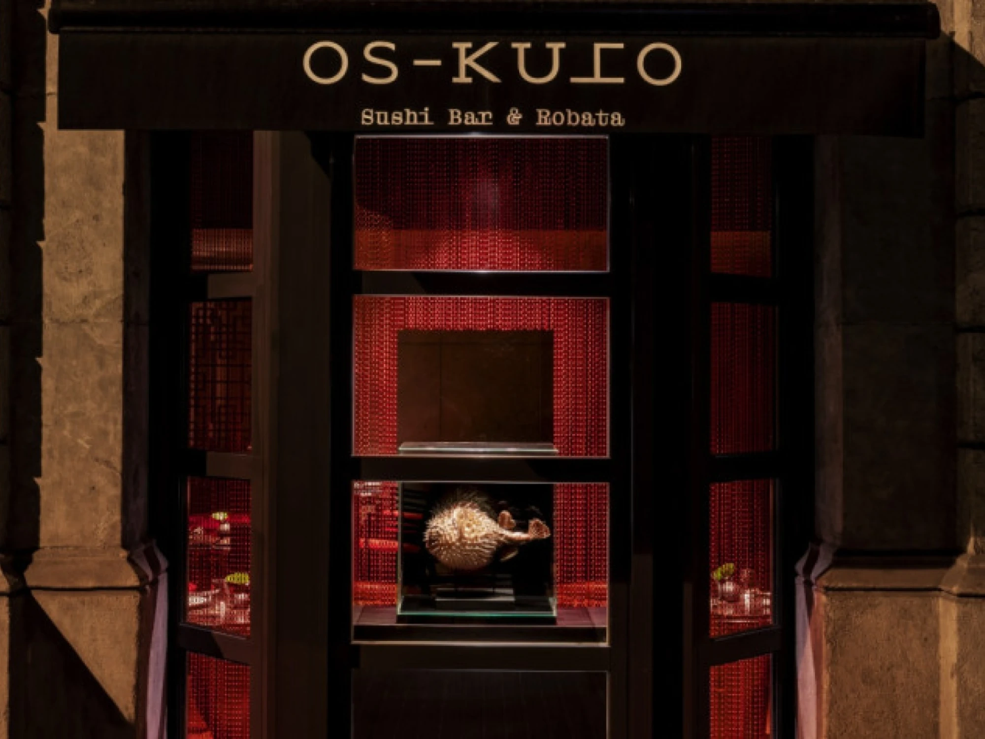 Imagen que muestra el interior de un restaurante de sushi con un estilo moderno y elegante, con detalles en madera y una iluminación cálida que crea un ambiente acogedor.