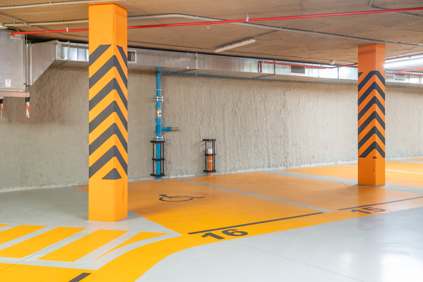 Espacio de parking cubierto con suelo señalizado y columnas con paneles decorativos.