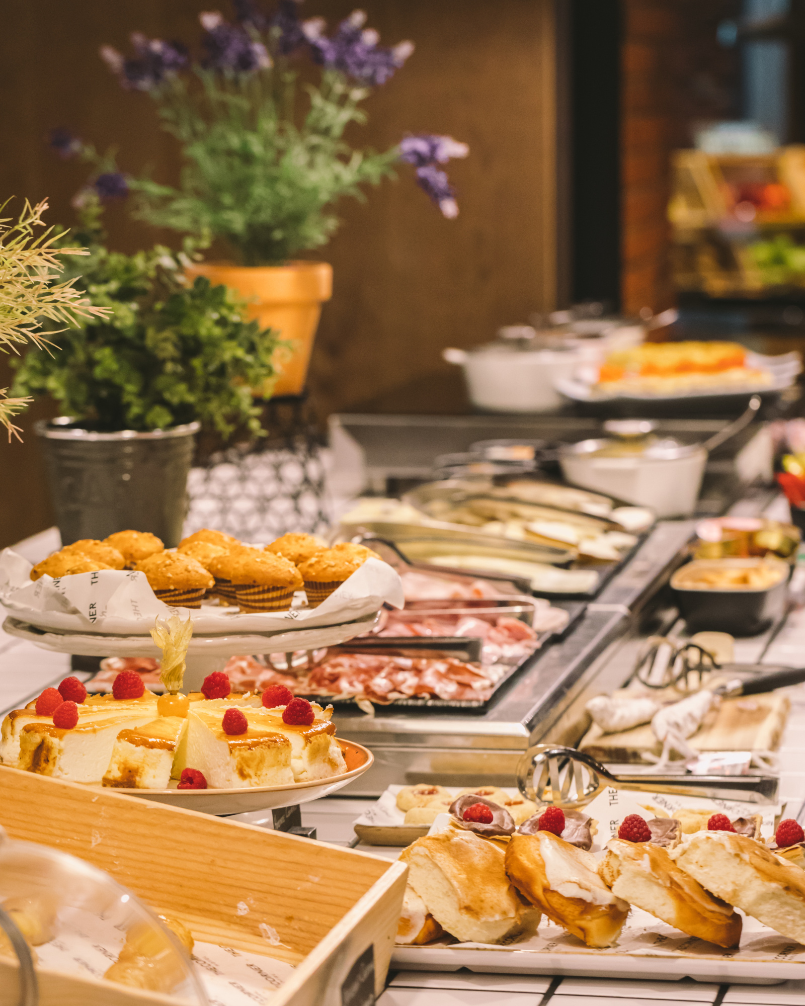 Se ve una mesa con bandejas de desayuno y dulces sobre estantes refrigerados.