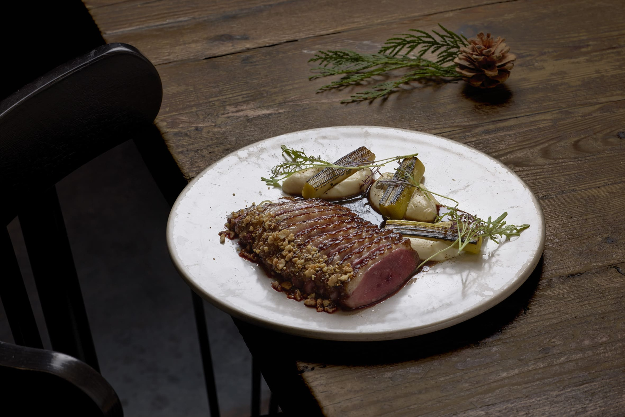 Sirven un plato con carne y vegetales sobre un plato blanco en una mesa de madera.