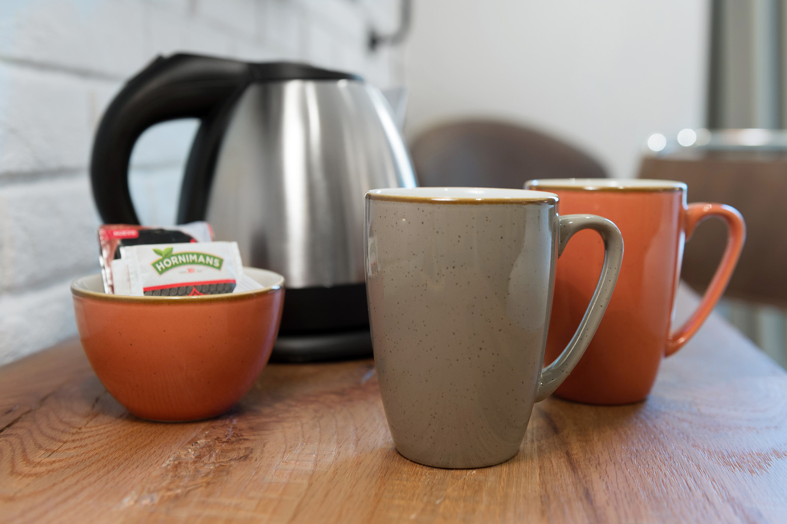 Hay una taza de café, tazas de desayuno y una cafetera sobre una mesa de madera.