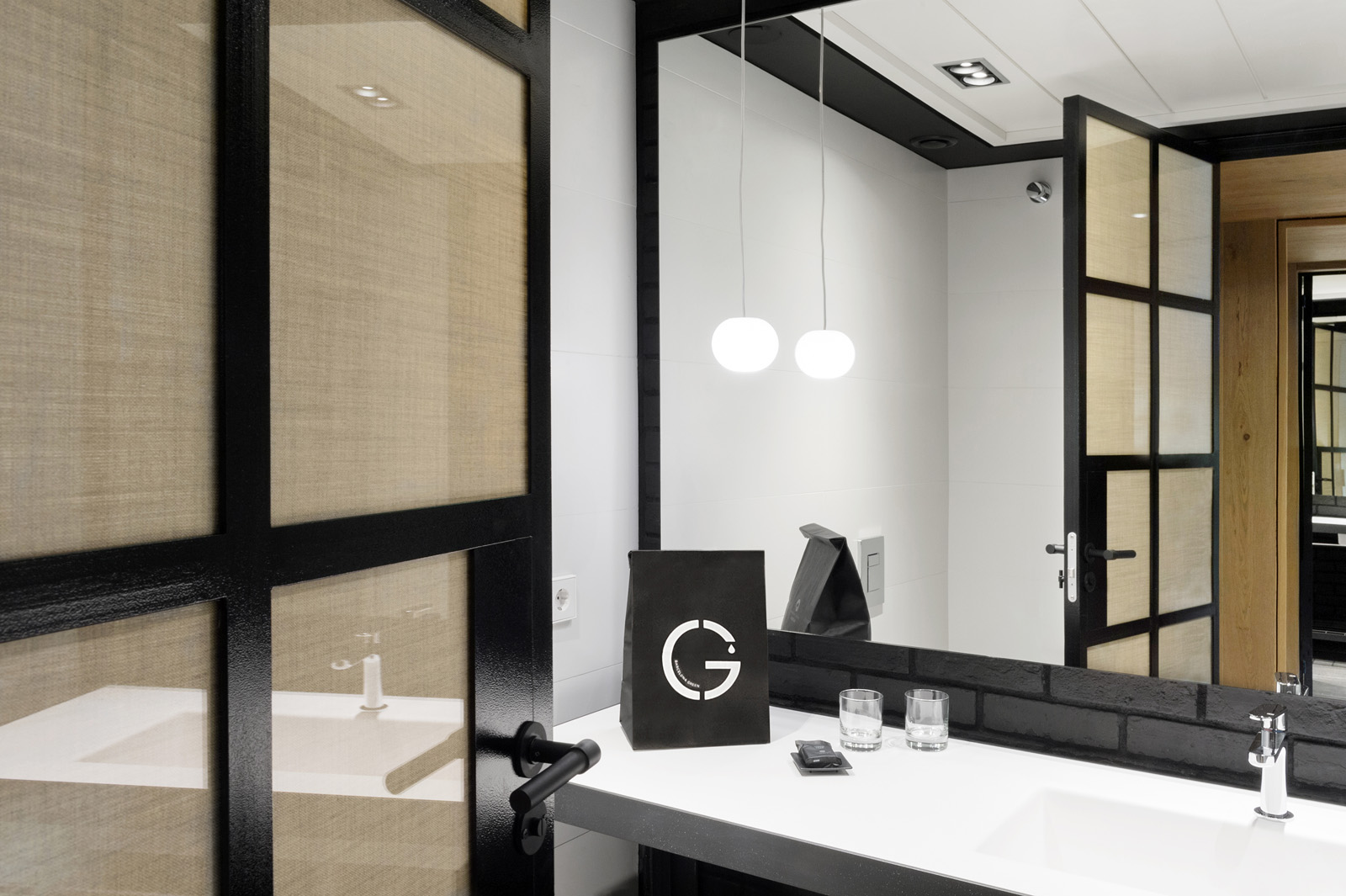 Baño moderno con lavabo doble, espejo iluminado y mamparas de vidrio.