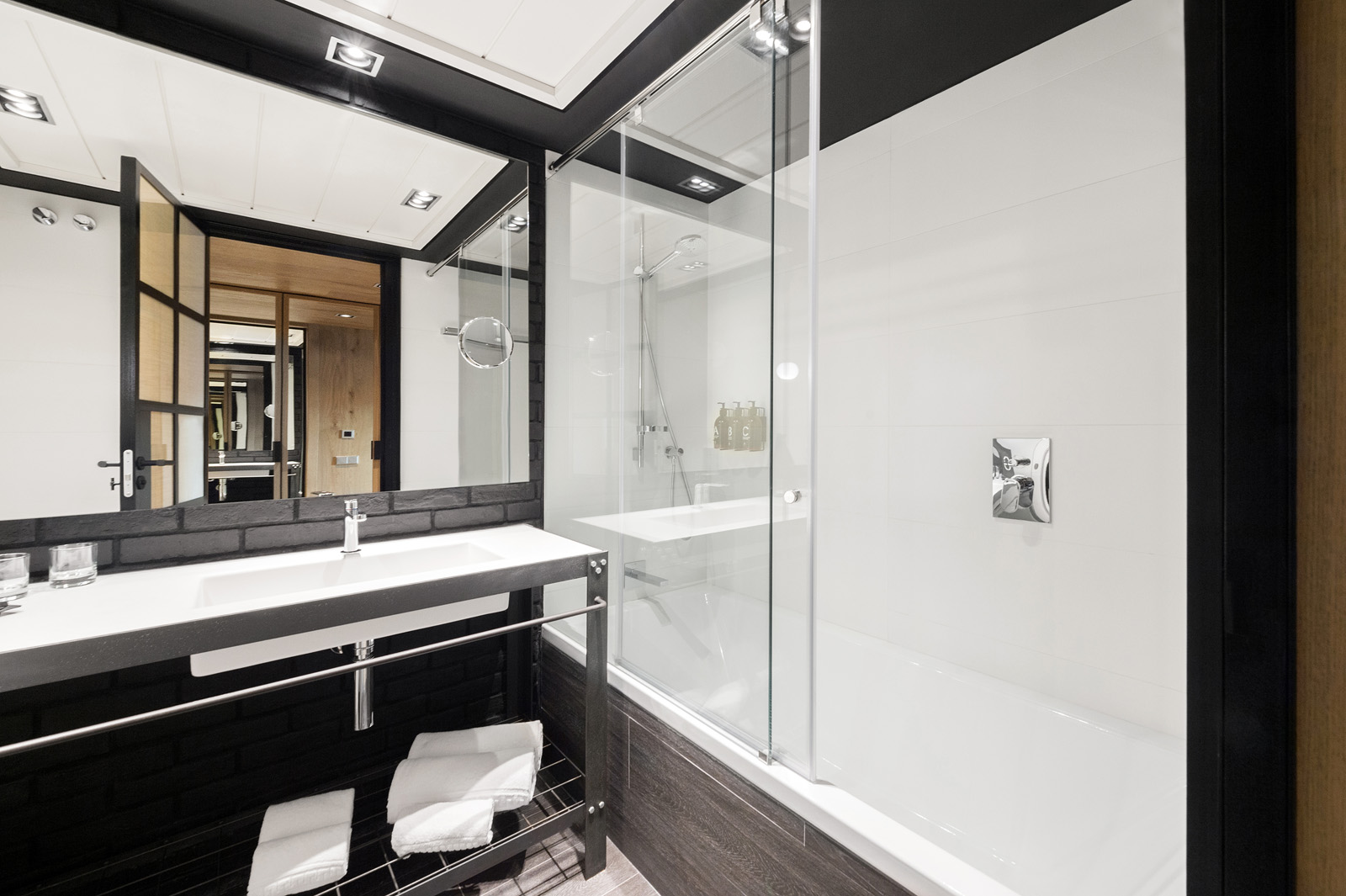 Baño moderno con lavabo doble, espejo y cabina de ducha con mampara de vidrio.