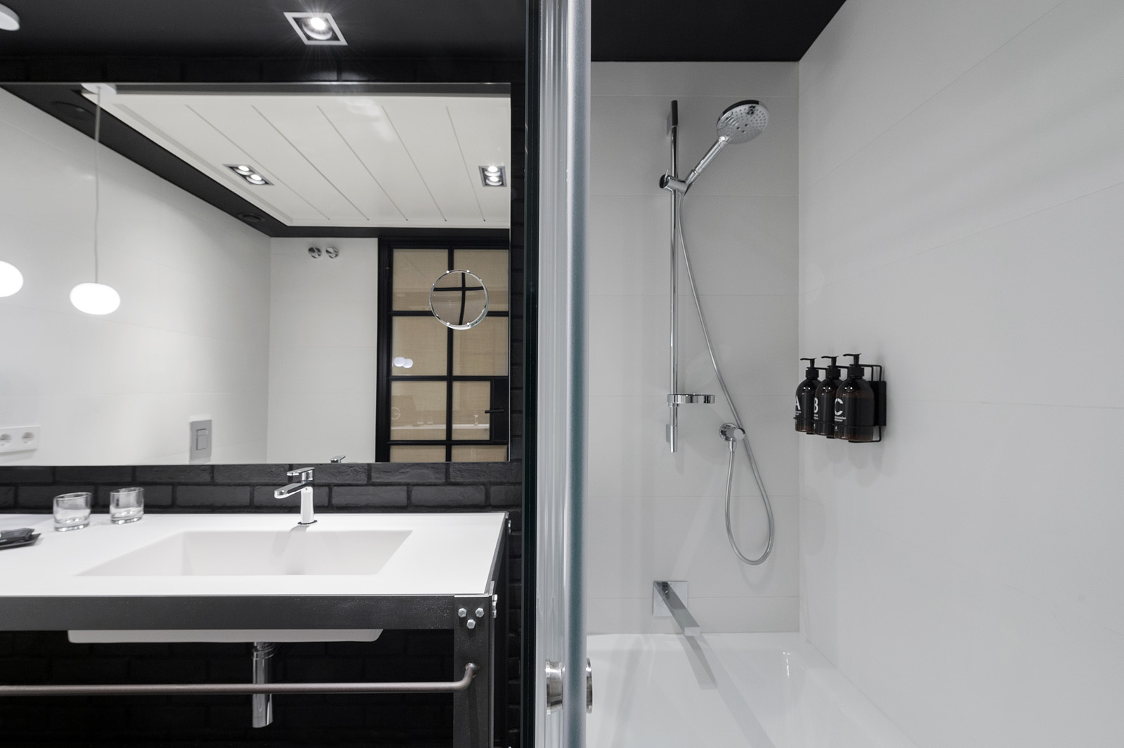 Baño moderno con lavabo, ducha y mampara de cristal en un espacio blanco y minimalista.