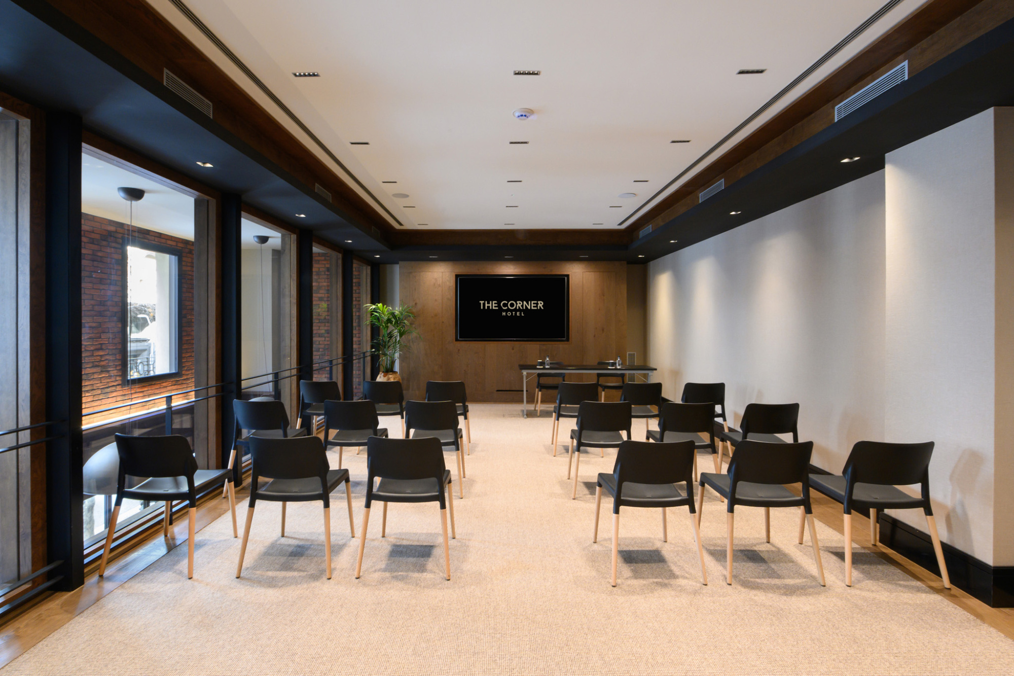 Sala interior con mesas y sillas negras, luz natural por ventanas y decoración moderna.