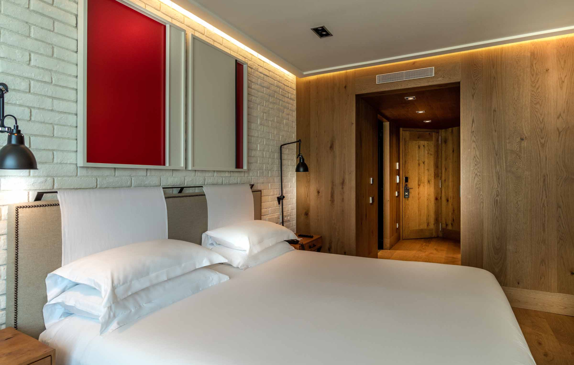 Presenta una cama doble con ropa de cama blanca y una pared con detalles iluminados, en un dormitorio moderno.
