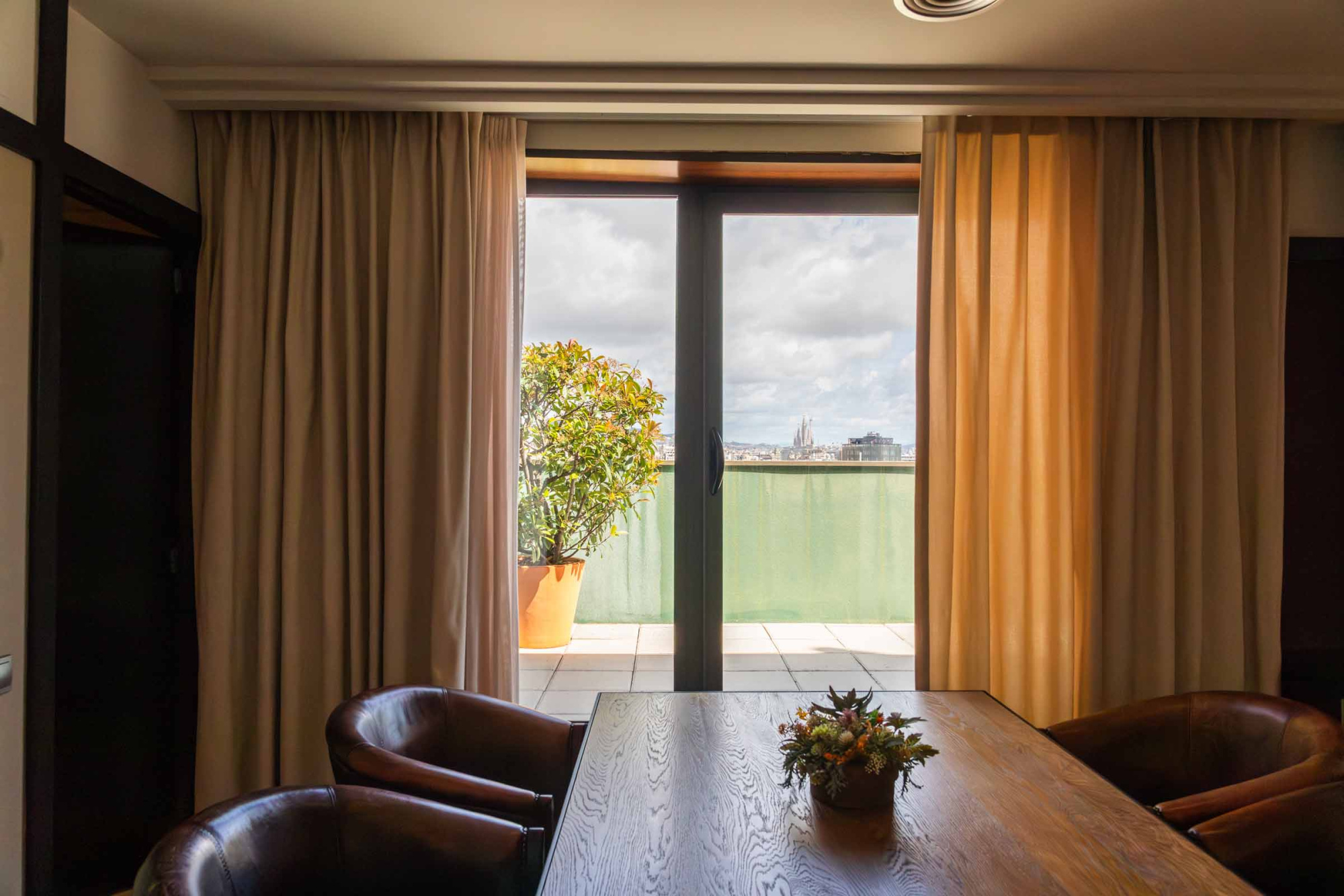 Se ve una sala con mesa de comedor, sillas de cuero y un ventanal con luz natural.