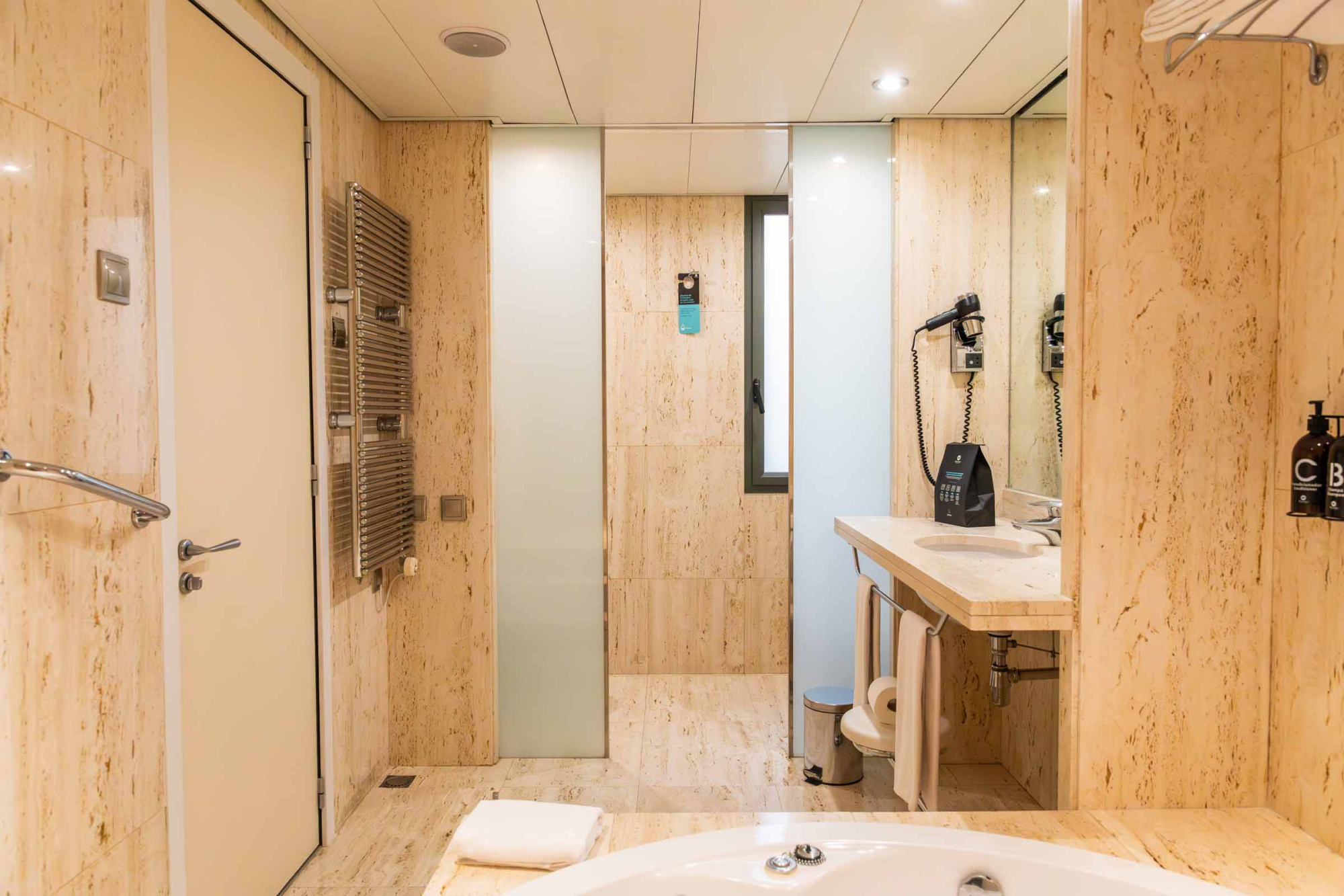 Se ve un baño moderno con ducha, mampara de vidrio y un lavabo con encimera de piedra.