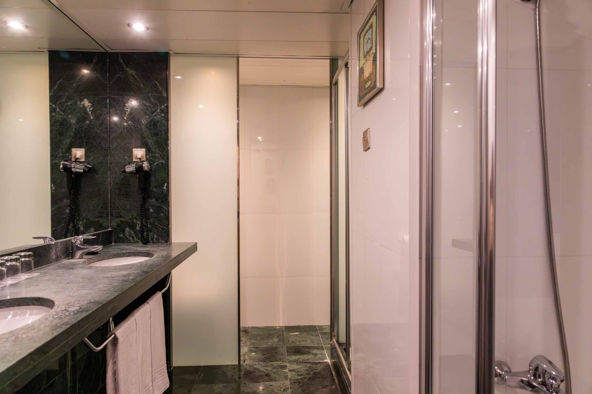 Se ve un cuarto de baño con lavabo, mampara de ducha y puerta corredera junto al espejo.