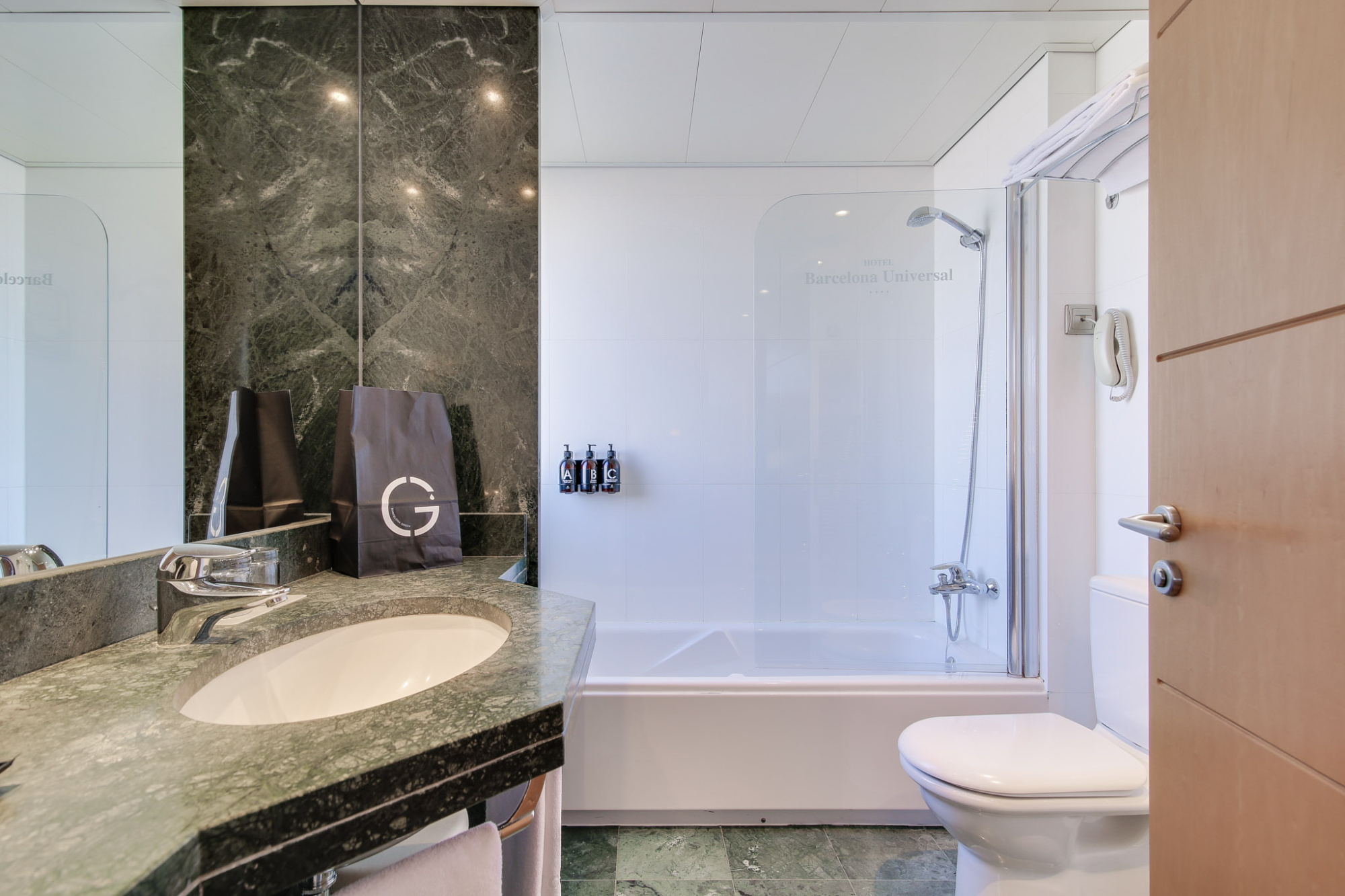 Se ve un baño con lavabo doble, pared de piedra y una bañera con ducha.