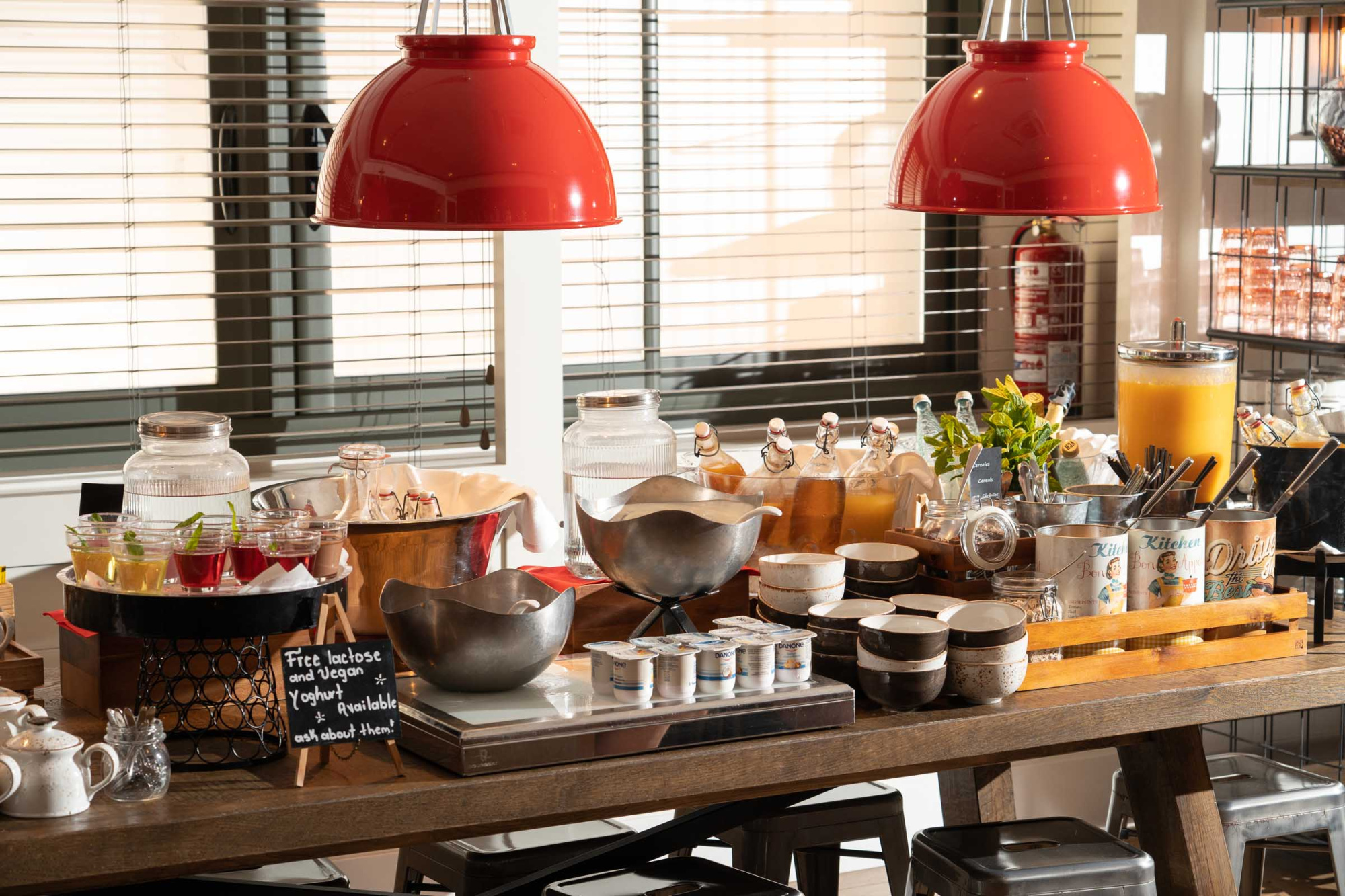 Se ve una mesa de buffet con recipientes, utensilios y botellas sobre un mostrador de madera.